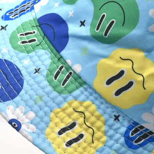 Close-up of dual-sided bucket hat featuring graffiti smiley prints and twill texture