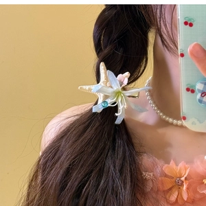 Detail einer Blumen-Seestern-Haarspange an geflochtenem Haar für den Strandurlaub
