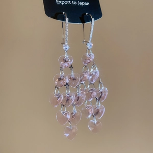 Detail of pink crystal heart tassel earrings with silver hooks and sparkling rhinestones