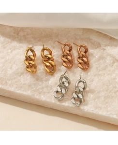 Nahaufnahme von Panzerketten-Ohrringen in Gold, Roségold und Silber auf Stein