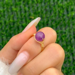 Detailed macro view of handmade gold wire wrapped ring with a round purple crystal stone