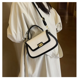 Détail du sac bandoulière bicolore en cuir à grain litchi avec boucle dorée élégante