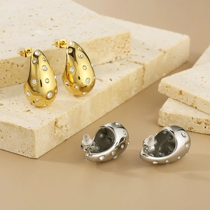 Detailed view of polished teardrop earrings in gold and silver with zircon accents