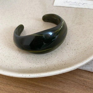 Detailed close-up of dark green marble resin cuff bracelet on beige ceramic tray