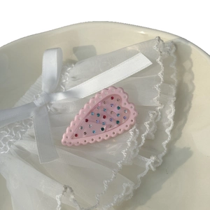 Pink acetate heart hair clip with colorful rhinestones on elegant white lace background