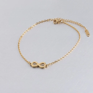 Detailopname van het gepolijste gouden infinity-symbool op een verfijnde armband