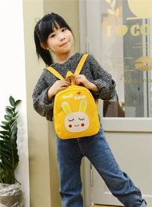 Detail of yellow canvas kids backpack with cute rabbit pattern worn by a small girl