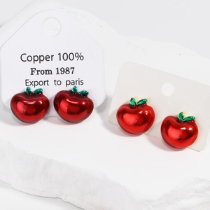 Gros plan de boucles d'oreilles pomme rouge en cuivre avec émail rouge vif brillant