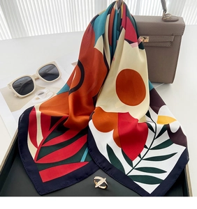 Close-up of printed silk scarf with floral patterns on a handbag in a lifestyle setting