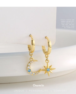 Macro detail of asymmetric star and moon gold earrings with blue and white zircon stones