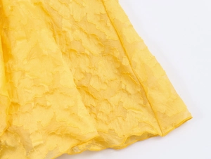 Close-up of yellow floral jacquard fabric texture on a French style holiday dress