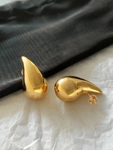 Macro shot of polished 18K gold teardrop earrings with a smooth reflective mirror finish