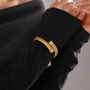 Close-up of golden spiral snake bracelet worn over a black sleeve highlighting metallic shine
