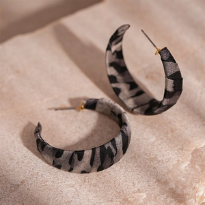 Close-up of C-shaped hoop earrings featuring vintage black and grey zebra fabric texture