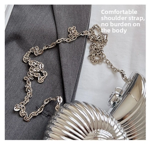Macro shot of silver snail-shaped evening clutch bag with refined metal texture and chain