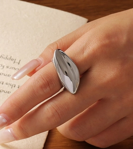 Polished silver melon seed shape ring with a wide geometric surface worn by a model