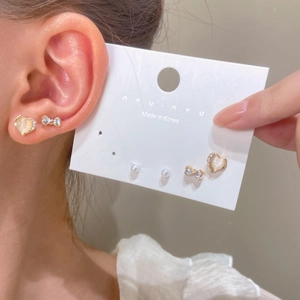 Detalle del set de pendientes con perlas, lazos de strass y corazones