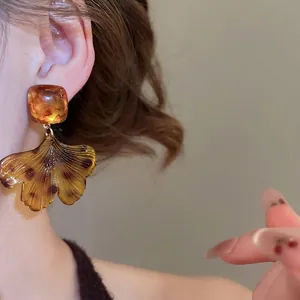 Boucles d'oreilles élégantes en acrylique ambre avec feuilles de ginkgo et clous carrés
