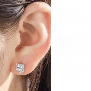 Close-up of heart-shaped light blue zircon earring with pavé setting on ear