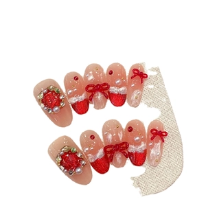 Short red press-on nails with 3D resin bows, glitter gradient, and pearl accents