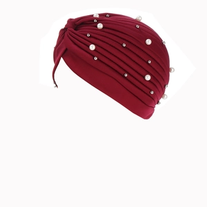 Detail of burgundy turban hat with pleated design, white pearls and silver metal beads