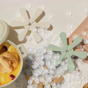 Three flower-shaped silicone trivets in cream, green and brown for heat protection