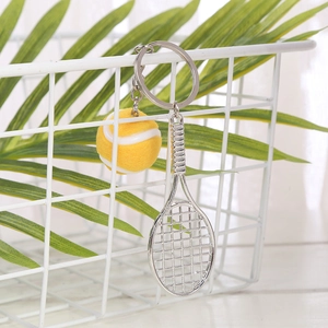 Close-up of a mini yellow tennis ball and silver racket keychain on a mesh basket