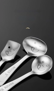 Close-up of matte 304 stainless steel spoons featuring laser-engraved smiley face detail