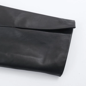 Close-up of black faux leather texture and stitching detail on the long coat sleeve
