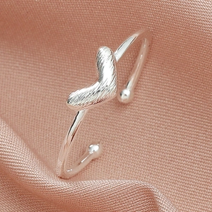 Minimalist silver heart open ring with a textured finish on a pink silk background
