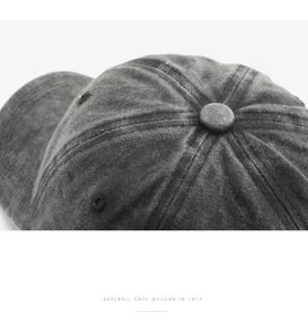 Macro detail of dark grey washed cotton baseball cap with retro stitching and top button