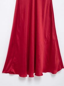 Détail du tissu en satin rouge élégant avec fini brillant soyeux et ourlet drapé en A