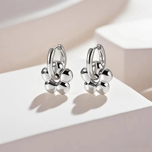 Detailed view of silver flower-shaped hoop earrings with rounded metallic petals on a tray