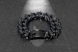 Detail of a punk style black stainless steel skull link bracelet on a textured dark background
