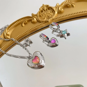 Detail of silver jewelry set with pink heart and star pendants featuring rhinestone borders