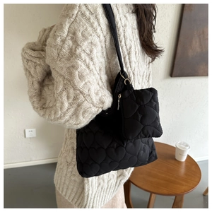 Detail view of black heart-quilted tote bag featuring a matching small coin purse attachment