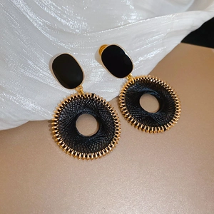 Dettaglio del filo nero intrecciato su base in metallo dorato e orecchini ovali