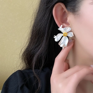 Macro view of vintage French style flower earrings with matte silver petals and gold center
