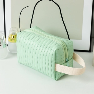 Dettaglio del beauty case trapuntato verde menta in pelle PU con manico e zip di chiusura