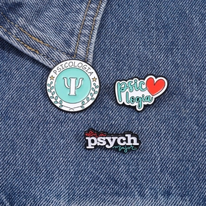 Psychology enamel pin set with Psi symbols and text pinned on blue denim fabric texture