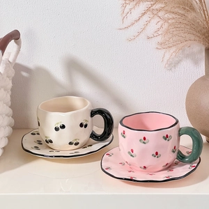 Detail of handmade heart and cherry patterned ceramic coffee cups with wavy edges