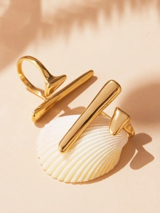 Detailed macro shot of gold geometric stainless steel rings on shell with palm shadows