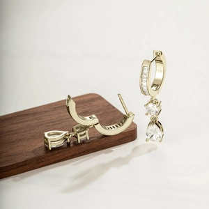 Retro gold drop earrings with circular and teardrop crystal pendants on a wooden display