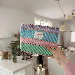 Detailed close-up of a colorful woven makeup bag with purple and green stripes