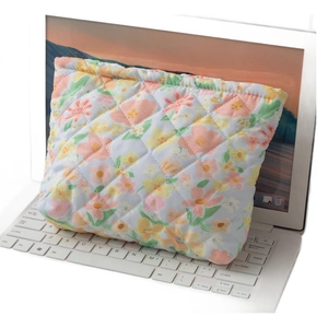 Quilted floral makeup bag in light blue fabric shown resting on a white laptop