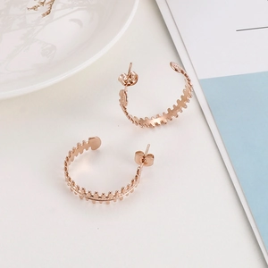 Macro detail of rose gold C-shaped hoop earrings with unique fishbone serrated texture