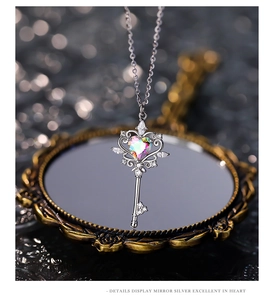 Detail view of silver key pendant with heart-shaped gemstone reflected on a vintage mirror