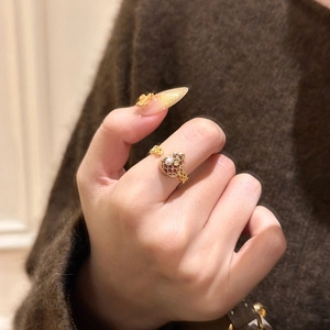 Detailansicht eines vergoldeten Flaschenkürbis-Rings mit Emaille und Perle am Finger