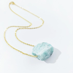 Detailed macro view of raw blue crystal stone pendant on a delicate gold metal chain necklace