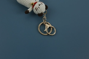 Detail of handmade crochet cat keychain featuring white yarn and gold metal lobster clasp